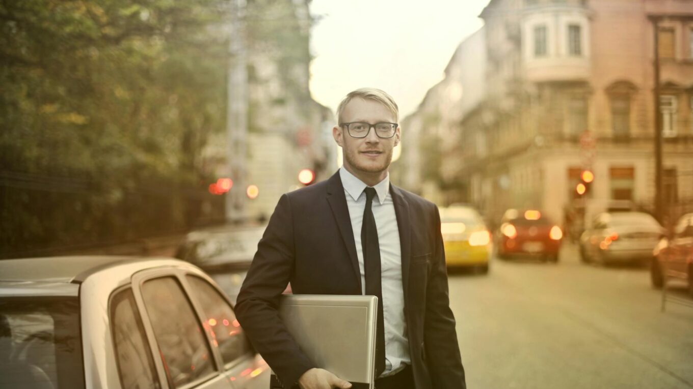 determined smiling businessman with laptop on street